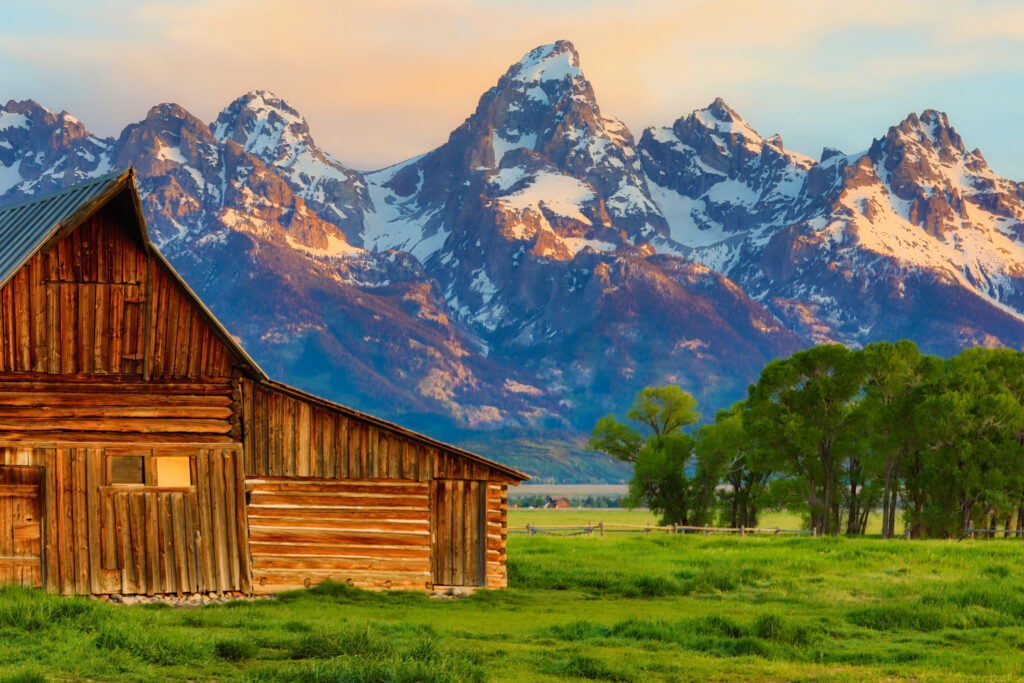 Historic wooden barn on the Mormon Row with the Grand Teton mountain range at sunrise, Jackson Hole, Wyoming.