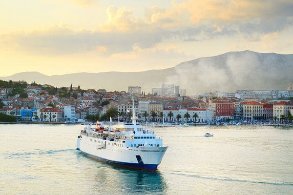 Passenger ferry in Split harbor, Croatia, with the city and mountains in the background.